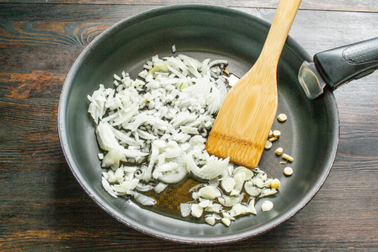 Sautéing Aromatics - Building a rich flavor base for the eggplant caviar. Chopped onion, parsley root, and garlic being sautéed in a skillet.