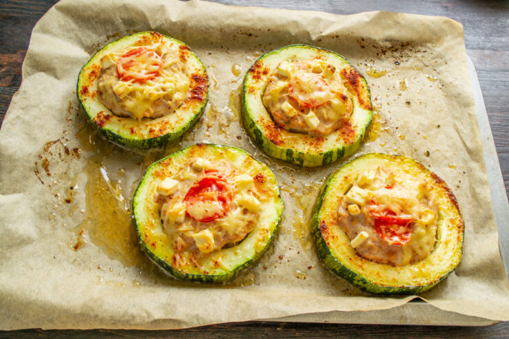 Placing the zucchini into the oven to bake. A baking sheet with stuffed zucchini rings being placed into a hot oven.