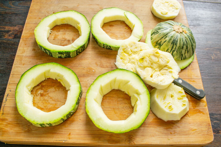 Coring the zucchini slices to make rings for stuffing. A hand using a small knife to remove the seedy core from a zucchini slice.