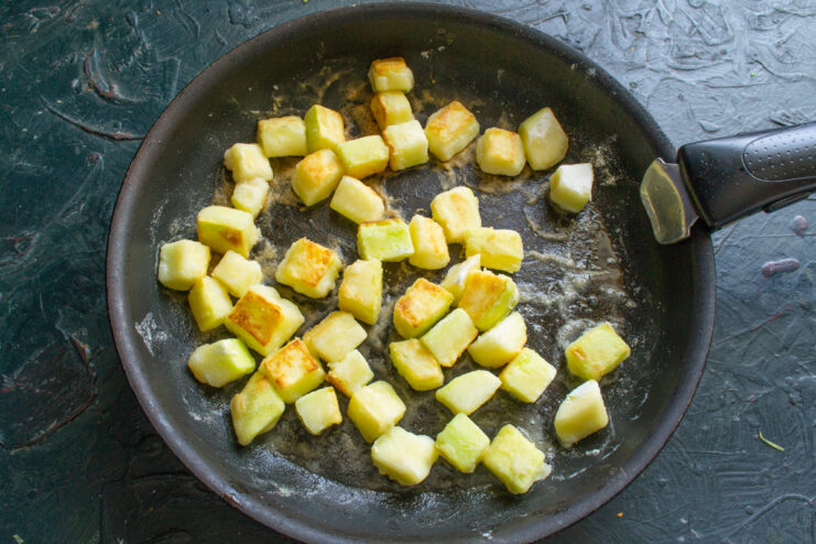 Frying Zucchini Until Golden for a Richer Flavor Flour-dusted zucchini cubes being fried to a golden brown in a skillet.