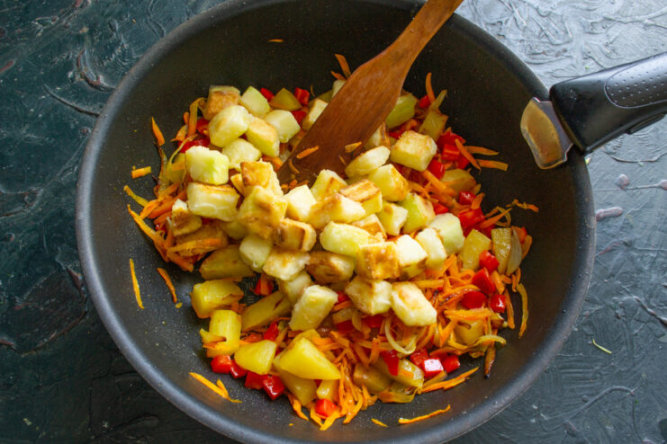 Adding Fried Zucchini to the Soup Pot Using a slotted spoon to transfer golden-fried zucchini into a pot with other vegetables.