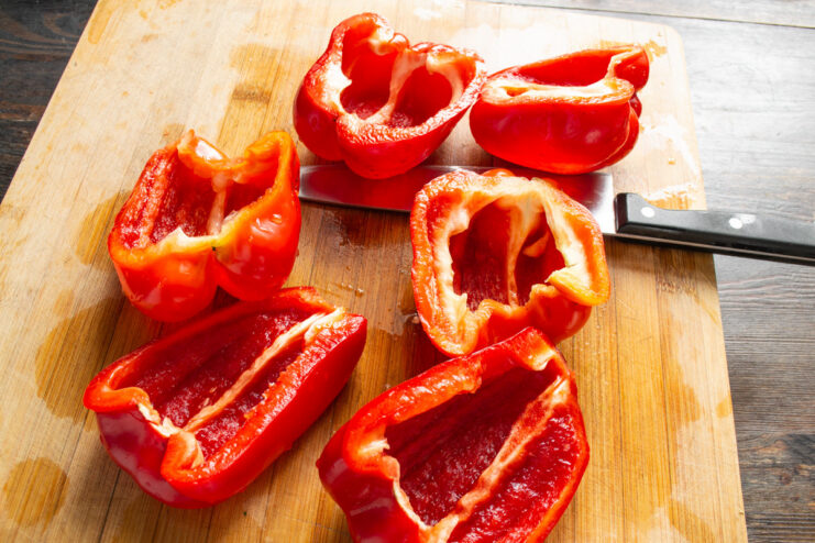 Cleaning Bell Peppers Before Freezing Red bell pepper halves being rinsed under a stream of water in a kitchen sink.