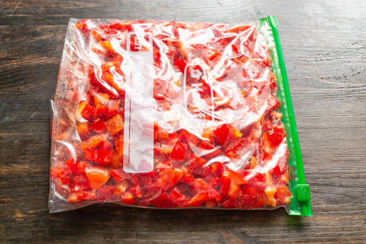 Tip: Removing Air from Freezer Bags to Prevent Freezer Burn Hands squeezing air out of a freezer bag filled with diced bell peppers before sealing it completely.