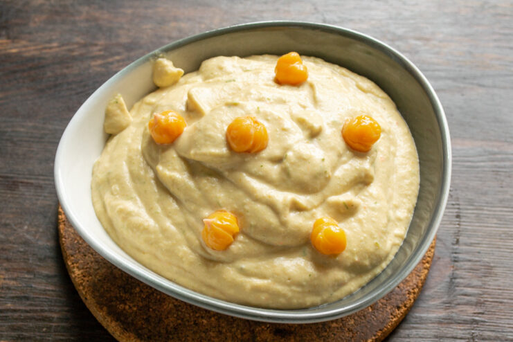 Storing the finished homemade hummus for later enjoyment. A glass jar filled with freshly made, creamy hummus, ready for storage.