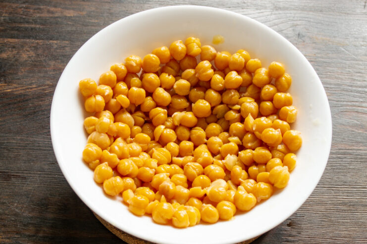 Perfectly soft and tender peeled chickpeas for the creamiest hummus. A close-up shot of peeled, soft chickpeas in a white bowl.