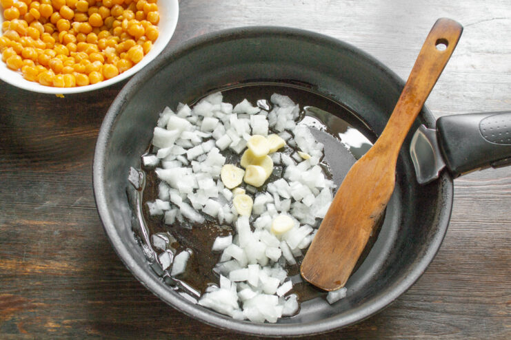 Preparing the aromatics: dicing the onion and slicing the garlic. Diced onion and sliced garlic on a cutting board, ready for sautéing.