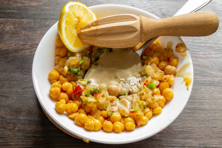 Squeezing fresh lemon juice for a bright, zesty flavor. Squeezing fresh lemon juice into the mixture for the hummus.