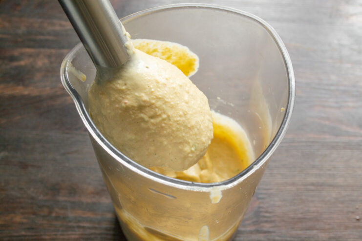 Using an immersion blender to achieve a perfectly smooth and creamy hummus. Blending hummus with an immersion blender until smooth and creamy.