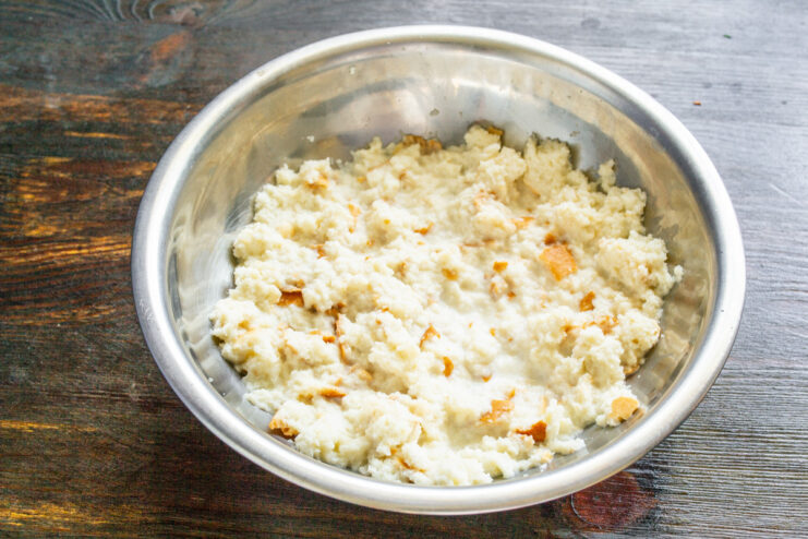 Soaking bread in milk to ensure juicy meatballs. Pieces of stale white bread soaking in a bowl of milk, a key step for tender tefteli.