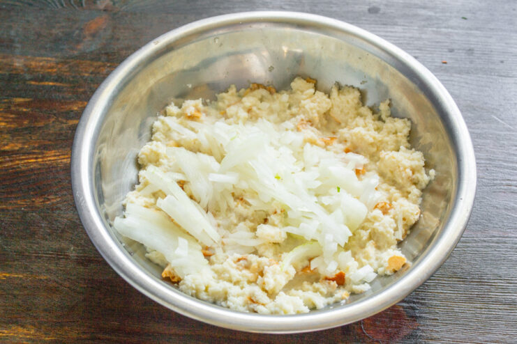 Dicing an onion to add flavor to the chicken meatball mixture. Finely diced yellow onion in a bowl, ready to be added to the meatball mix.