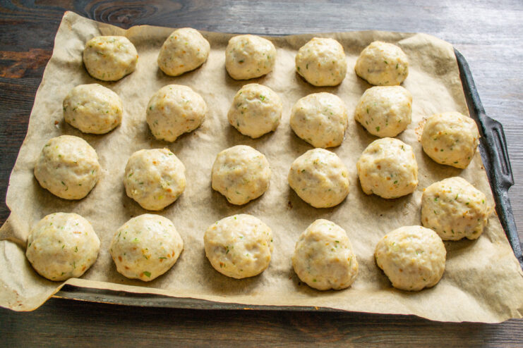 Baking the chicken tefteli until golden brown. A baking sheet full of chicken meatballs (tefteli) going into a hot oven.