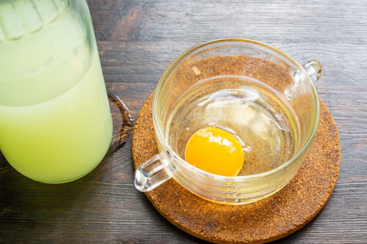 Adding an egg to the bottle for the pancake batter. An egg being added to a plastic bottle containing whey, using a funnel.