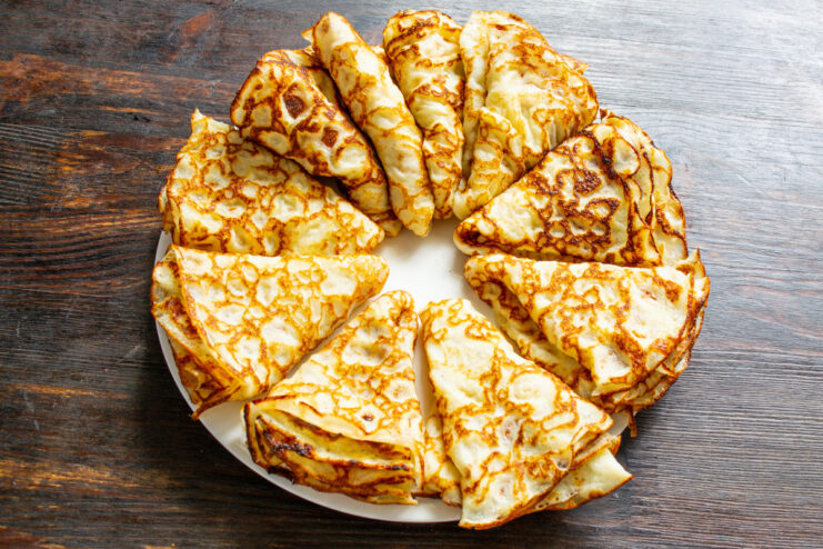 A beautiful stack of freshly made thin pancakes, ready to be served. A stack of freshly cooked thin pancakes on a plate, ready to be eaten.