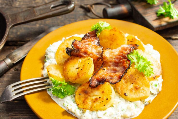 A plate of country-style potatoes with bacon and a creamy sauce, garnished with parsley.