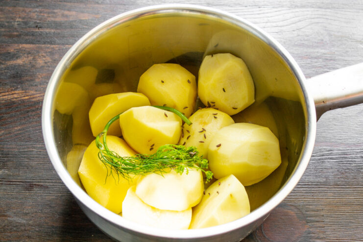 Step 1: Preparing the Potatoes for Boiling Peeled potatoes cut in half in a pot, ready for boiling.