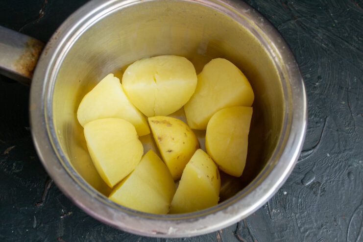 Preparing New Potatoes for the Greek-Style Dish Fresh new potatoes being washed and quartered on a cutting board.