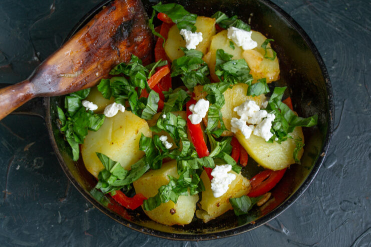 Adding Feta Cheese or Cottage Cheese for Creaminess Cubes of feta cheese being added to the pan with potatoes and peppers.