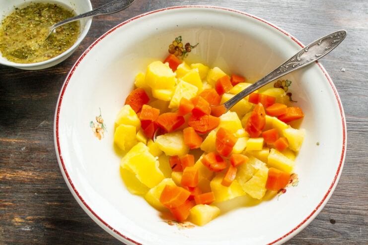 Adding Carrots to the Potato Salad Base Diced boiled carrots being added to a bowl of diced potatoes.