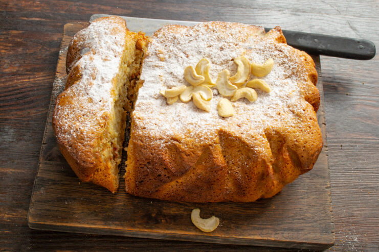 Enjoy a slice of moist condensed milk cake with your tea! A slice of the finished condensed milk cake with nuts and dates on a plate.