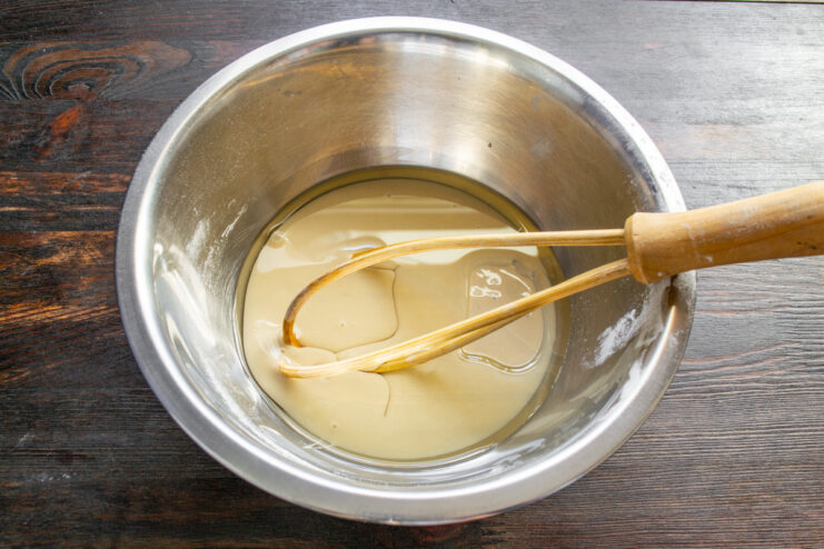 Step 2: Mixing the wet ingredients - condensed milk and oil. A glass bowl with condensed milk and oil being mixed.