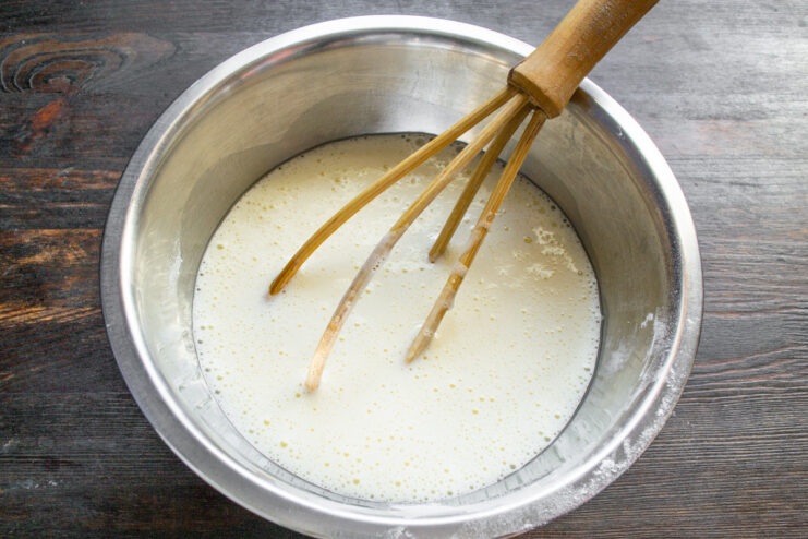 Step 3: Whisking eggs into the liquid mixture until smooth. Whisking eggs into the condensed milk and oil mixture in a glass bowl.