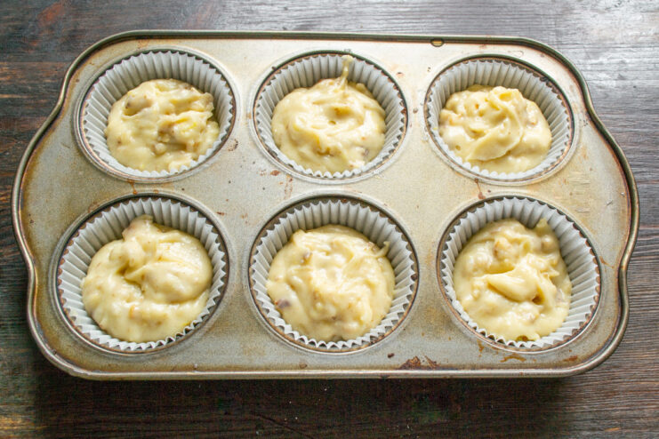 Filling muffin liners with batter, leaving room to rise Filling paper muffin liners in a tin with batter.