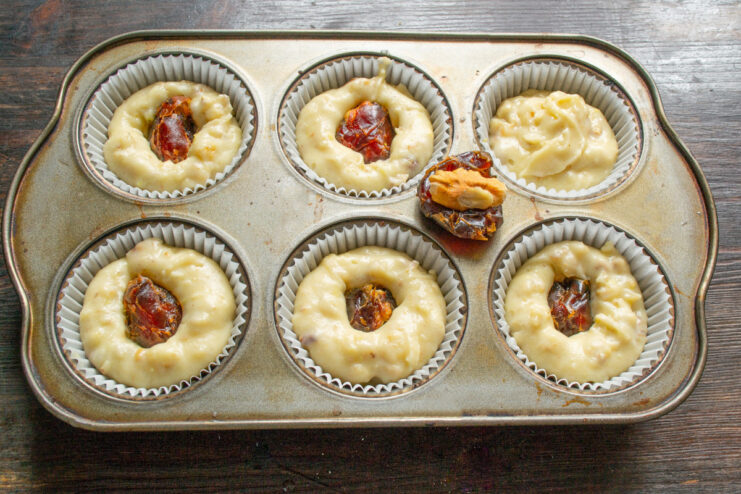 Creating the surprise filling: stuffing dates with walnuts A hand stuffing a pitted date with a piece of walnut.