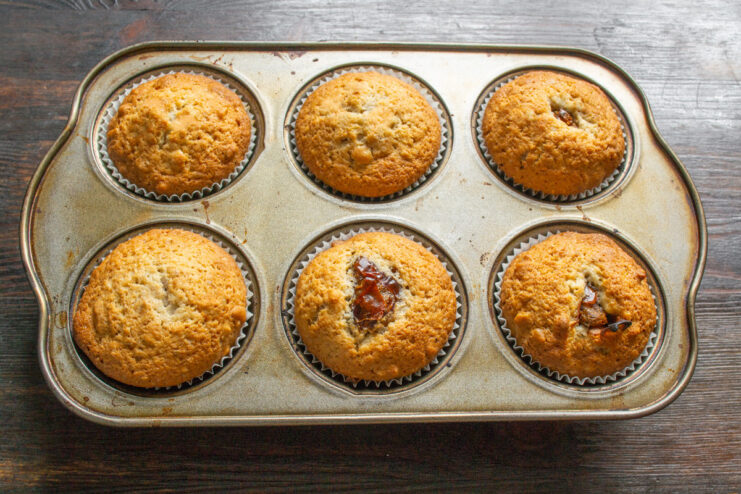 Baking the walnut and date muffins until golden brown A muffin tin with unbaked muffins being placed into an oven.