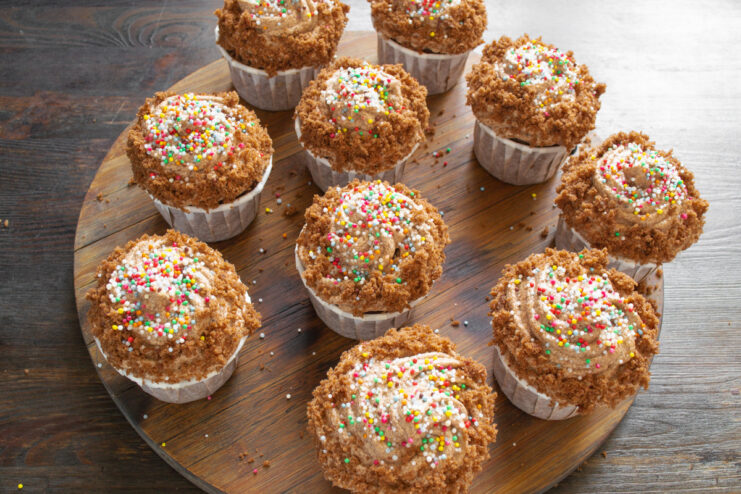 Final touch: Decorating cupcakes with colorful sprinkles Finished Coca-Cola cupcakes with chocolate frosting and colorful sprinkles on a plate.