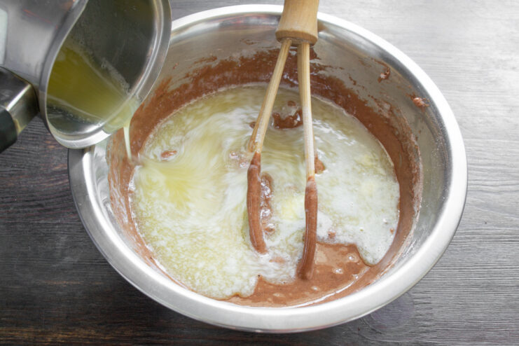 Step 4: Incorporating melted butter into the batter Pouring melted butter from a small saucepan into the cupcake batter.