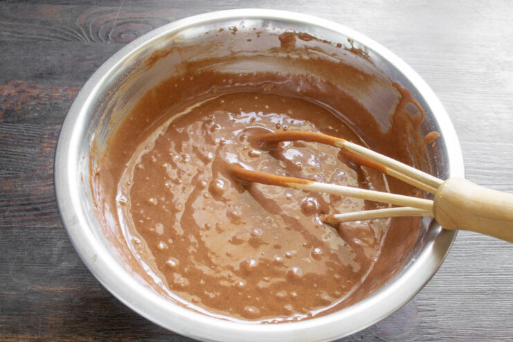 Step 5: Mixing the final cupcake batter until smooth A bowl of smooth, dark chocolate cupcake batter being mixed with a whisk.
