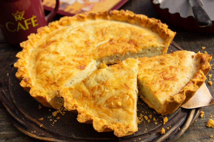 A whole baked onion and cheddar quiche in a tart pan, ready to be served.