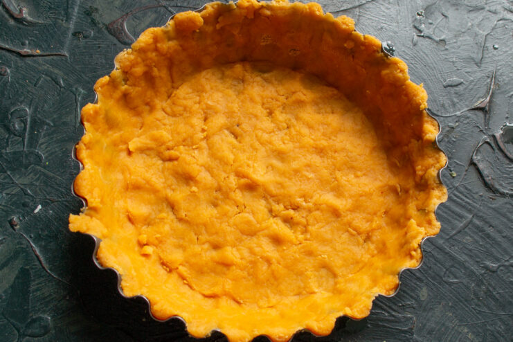 Lining the Tart Pan with Dough Pressing the rolled-out quiche dough into a fluted tart pan.