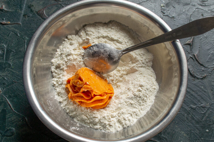 Making the Cheesy Quiche Dough A bowl of flour with a block of cheddar cheese butter being added to it.