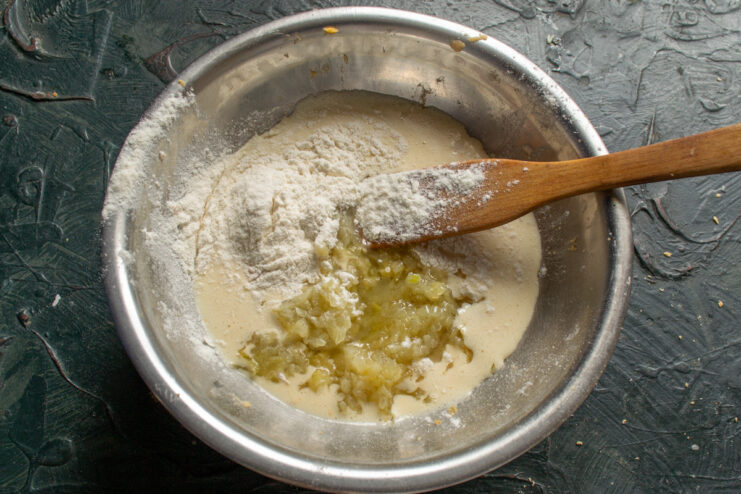 Adding Flour to Thicken the Filling Adding a spoonful of wheat flour to the egg and caramelized onion mixture in a bowl.