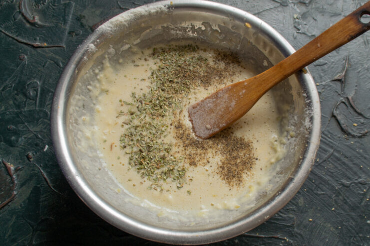 Seasoning the Onion and Egg Filling Seasoning the quiche filling with dried thyme, salt, and pepper in a bowl.