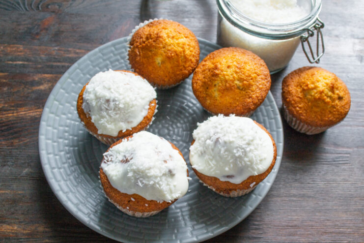 Decorating coconut cupcakes with cream and shredded coconut Frosting being applied to a cooled coconut cupcake, with shredded coconut sprinkled on top.