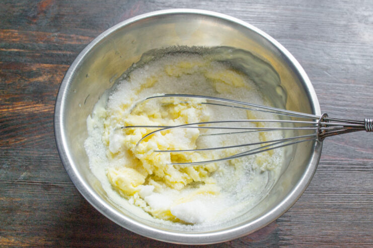 Creaming butter and sugar together for the cupcake base A hand whisking butter and sugar together in a glass bowl.