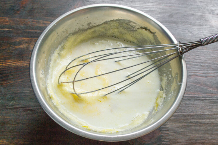 Incorporating coconut milk for a rich, tropical flavor Pouring coconut milk from a measuring cup into the batter bowl.