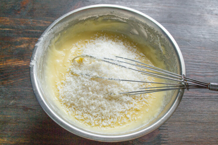 Adding shredded coconut for the signature cupcake flavor Adding a spoonful of shredded coconut to the cupcake batter.