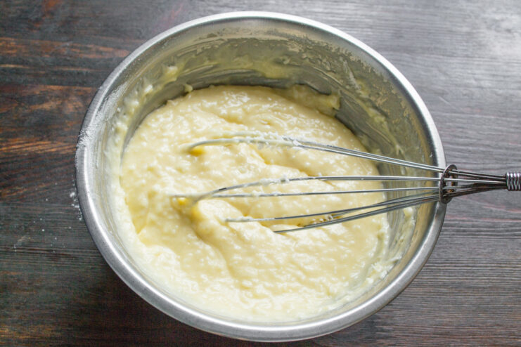Folding shredded coconut into the cupcake batter A spatula mixing shredded coconut into the batter in a glass bowl.