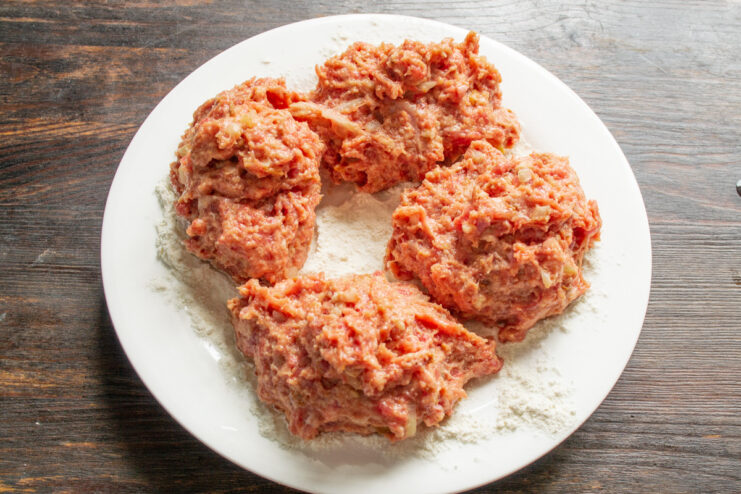 Portioning the Sausage Mixture The ground beef mixture divided into four equal portions in a bowl.