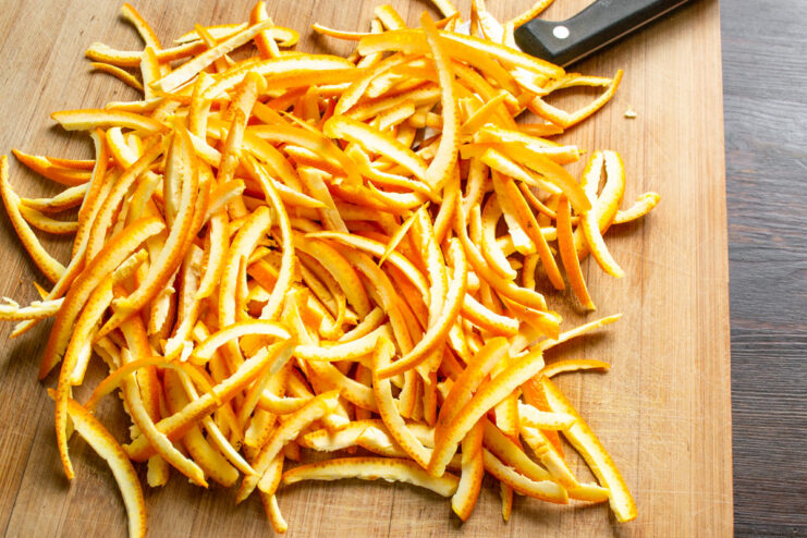 Preparing Orange Peels for Candying Close-up of orange peels being sliced into thin strips on a cutting board.