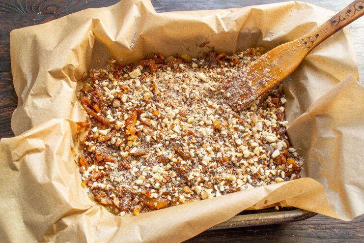 Topping with Crushed Almonds Crushed almonds being sprinkled over the layer of melted chocolate on the candied orange peels.