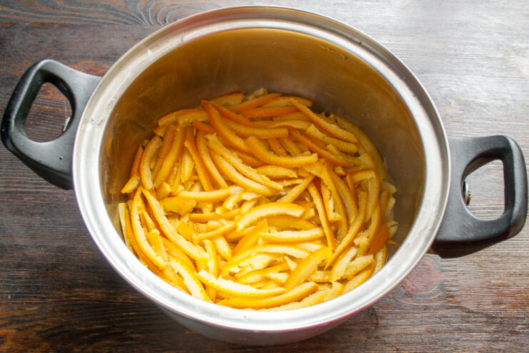 Simmering the Orange Peels Until Tender Orange peels simmering gently in a pot of water on the stove.