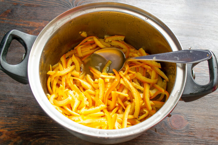 Adding Orange Peels to the Boiling Sugar Syrup Orange peels being added to a pot of simmering sugar syrup.