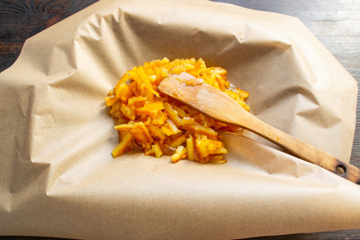 Spreading Candied Orange Peels to Dry Candied orange peels spread out in a single layer on a baking sheet lined with parchment paper.