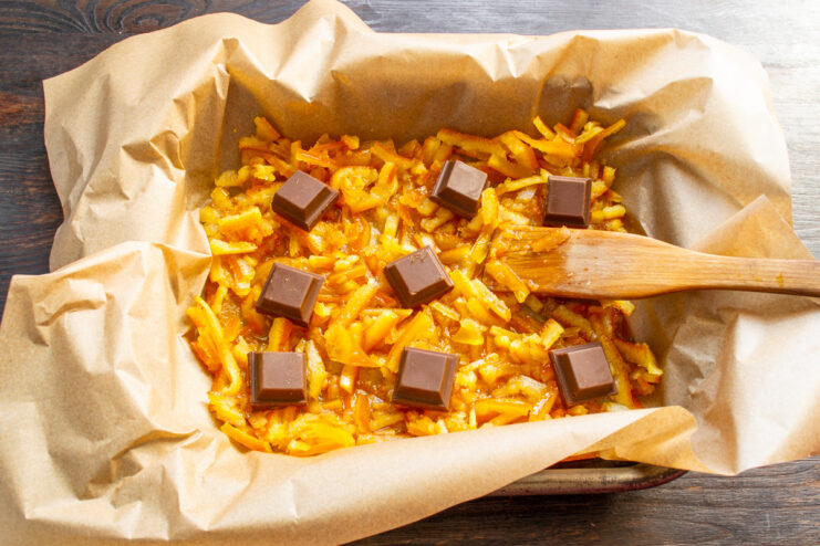 Adding Milk Chocolate to the Candied Peels Pieces of milk chocolate scattered over a layer of candied orange peels on a baking sheet.