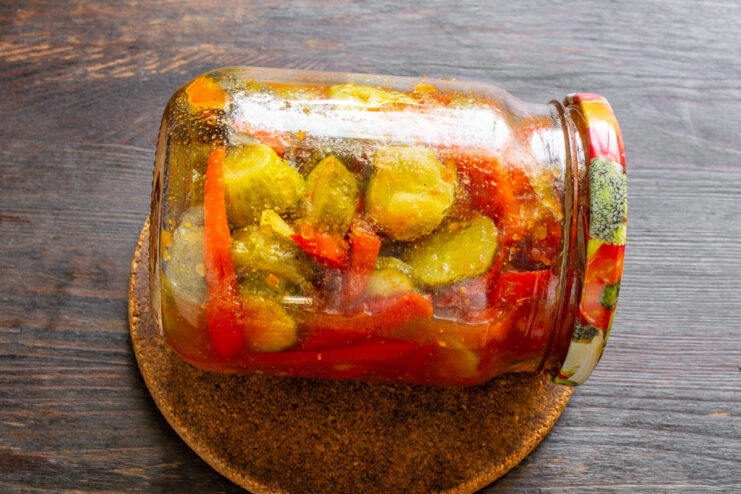 Cooling the canned salad jars upside down to ensure a proper seal. Sealed jars of Georgian cucumber salad standing upside down, wrapped in a blanket to cool slowly.