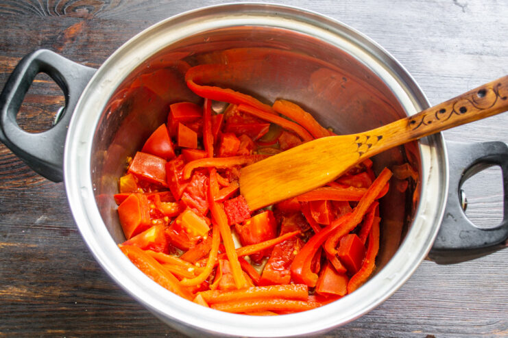 Simmering tomatoes and peppers to create the salad base. Tomatoes and peppers simmering in a large pot on the stove to make the salad base.